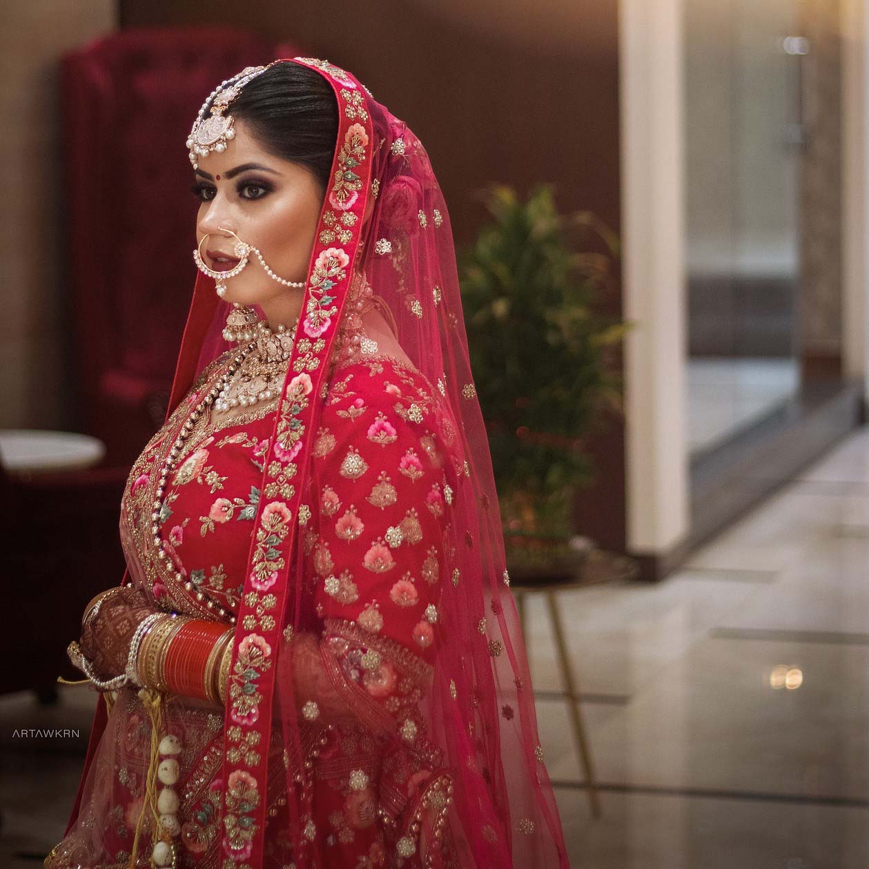 Traditional Hindu bride profile portrait wearing a red embroidered lehenga and veil.